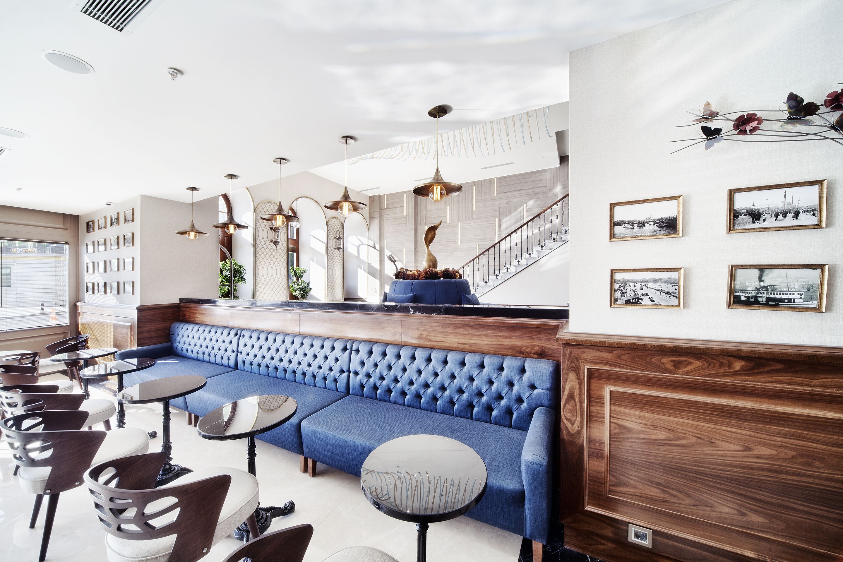 A modern lounge area with a blue sofa, round tables, and a staircase.