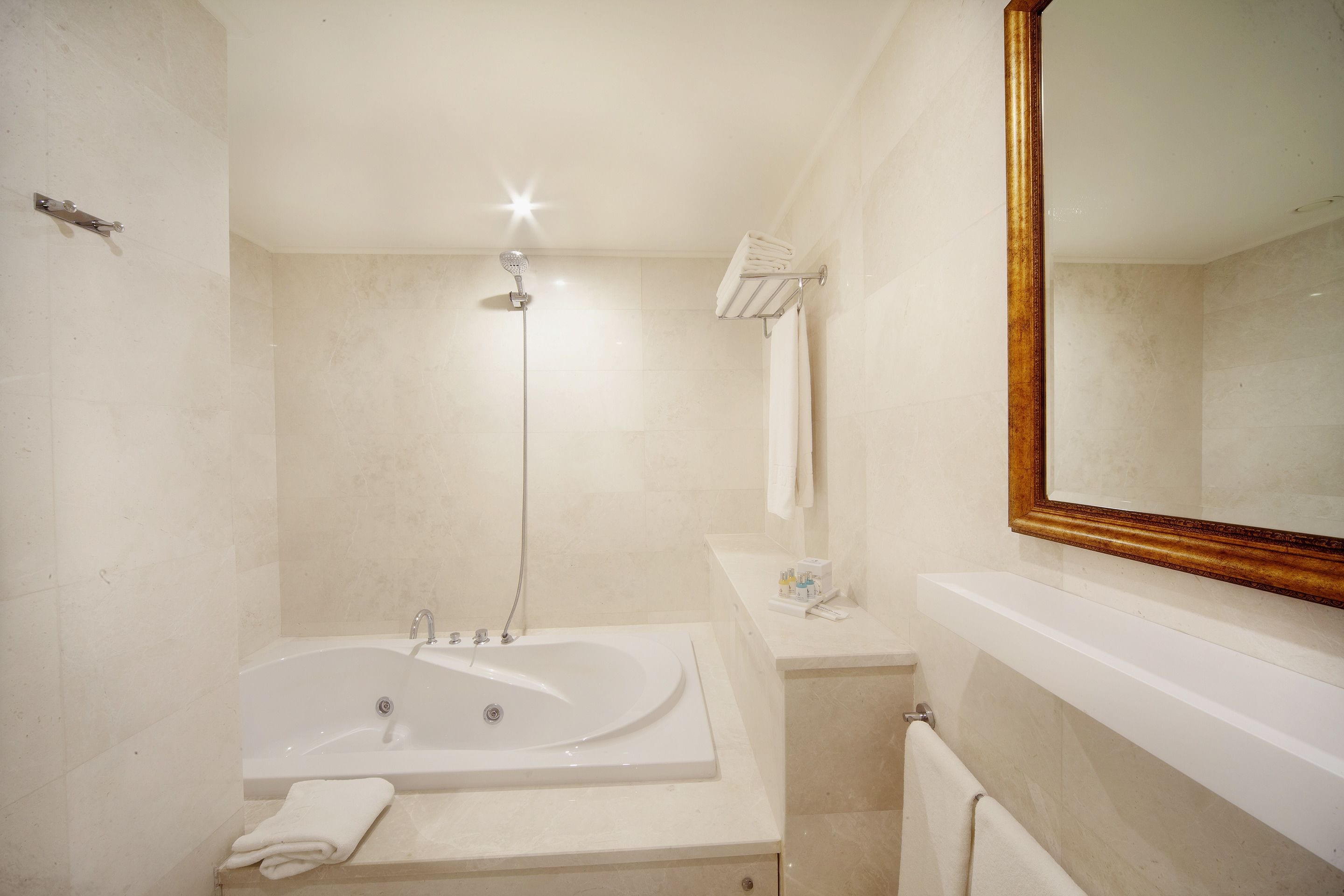 A bathroom with a large bathtub, a shower, a vanity with a mirror, and a towel rack.