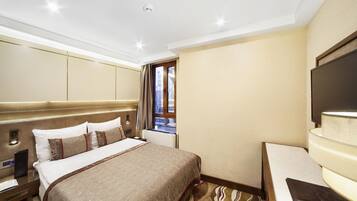 Habitación de hotel con una cama grande, escritorio, televisión de pantalla plana y ventana con vista a edificios.