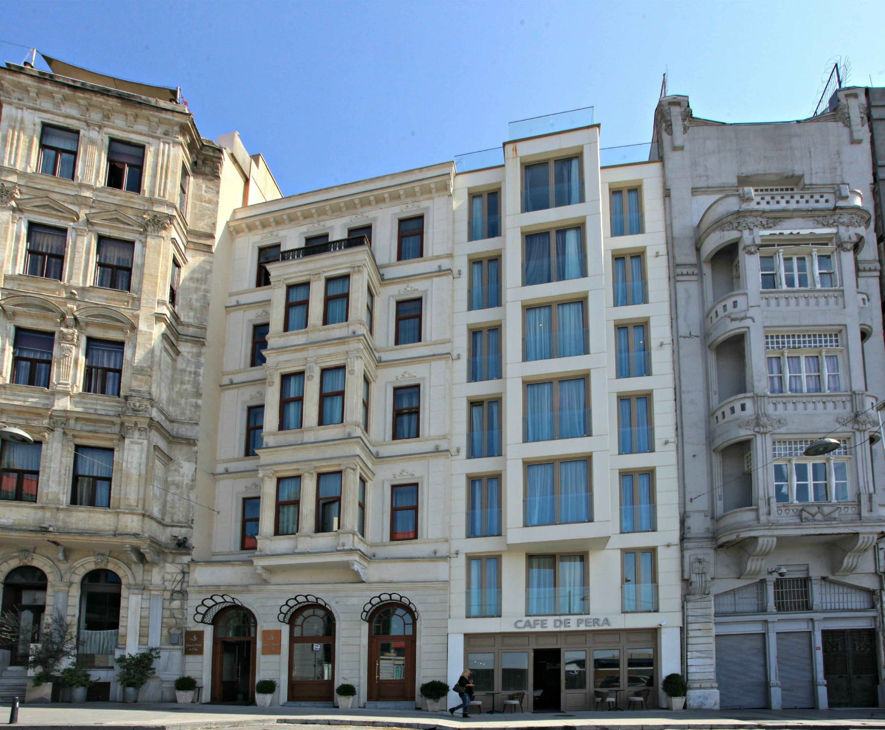 Un edificio de varios pisos con una cafetería llamada "CAFE DE PERA" en la planta baja.