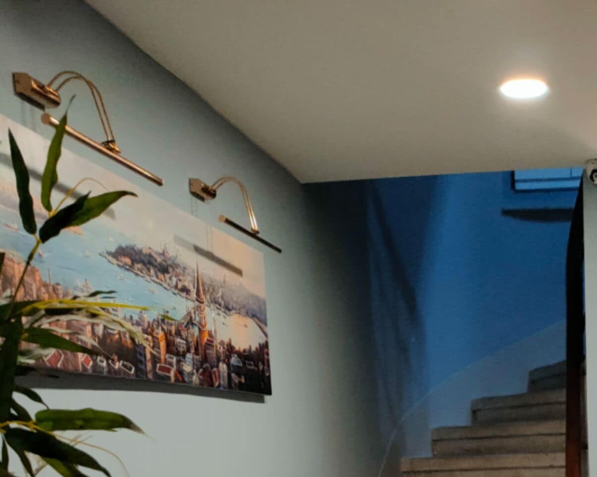 A staircase with a blue wall and a framed cityscape painting.