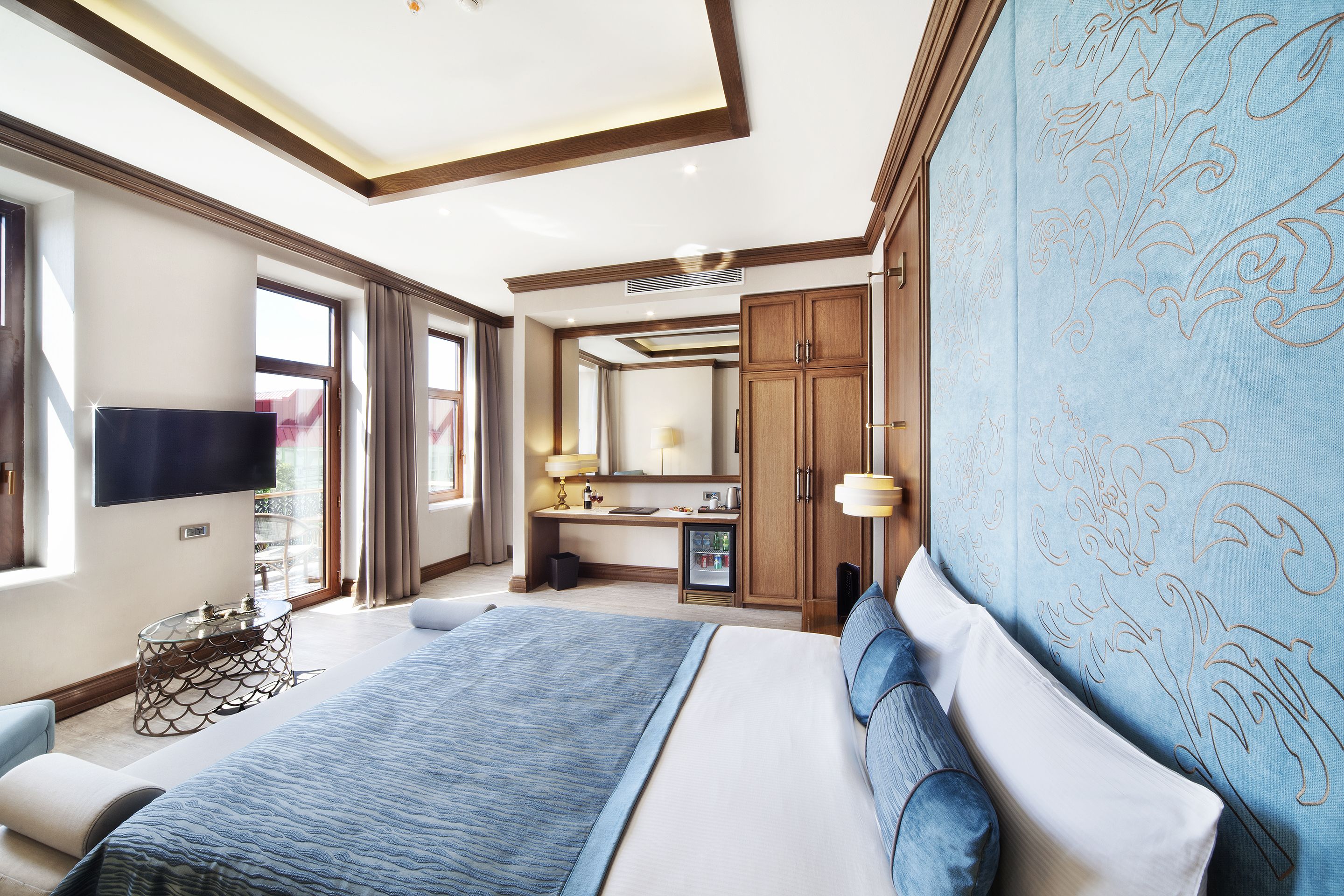 A hotel room with a large bed, a TV, a desk with a computer, and a bathroom.