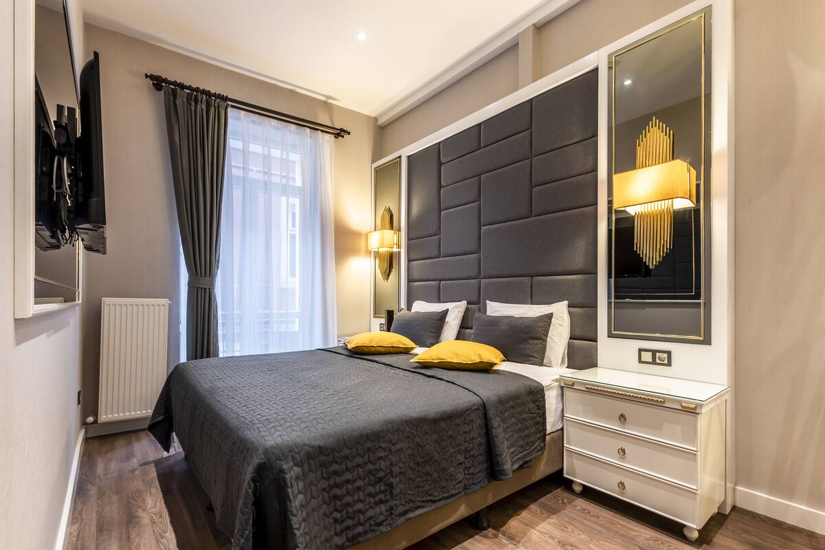 A modern bedroom with a large bed, bedside lamps, and a mirror.