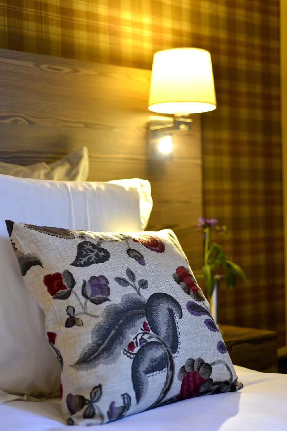 A bed with a white pillow and a decorative pillow with floral patterns.