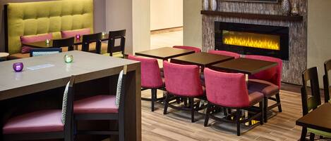 A hotel room with a seating area featuring a sofa and multiple tables and chairs.