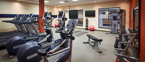 A gym with treadmills, elliptical machines, a bench, and various exercise equipment.