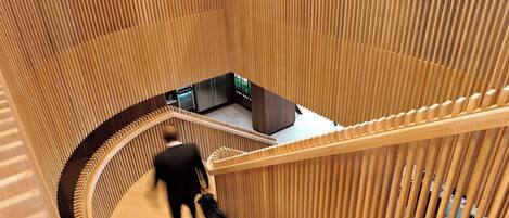 A spiral staircase with wooden railings and a person descending.