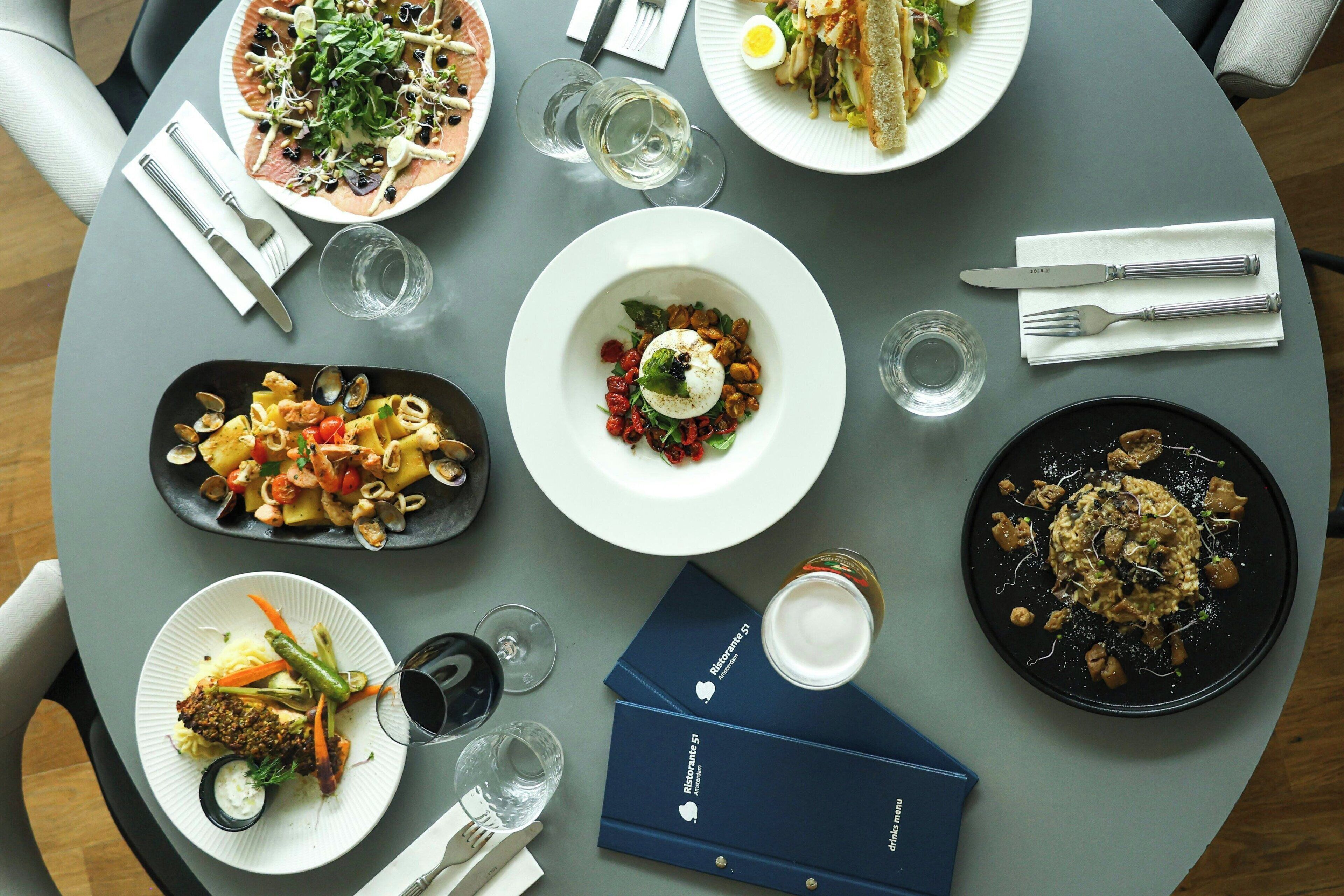 Una mesa redonda con varios platos, vasos y servilletas.