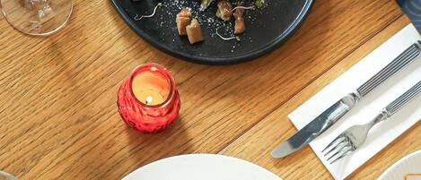A dining table with a plate of pasta, a glass of white wine, and a candle.