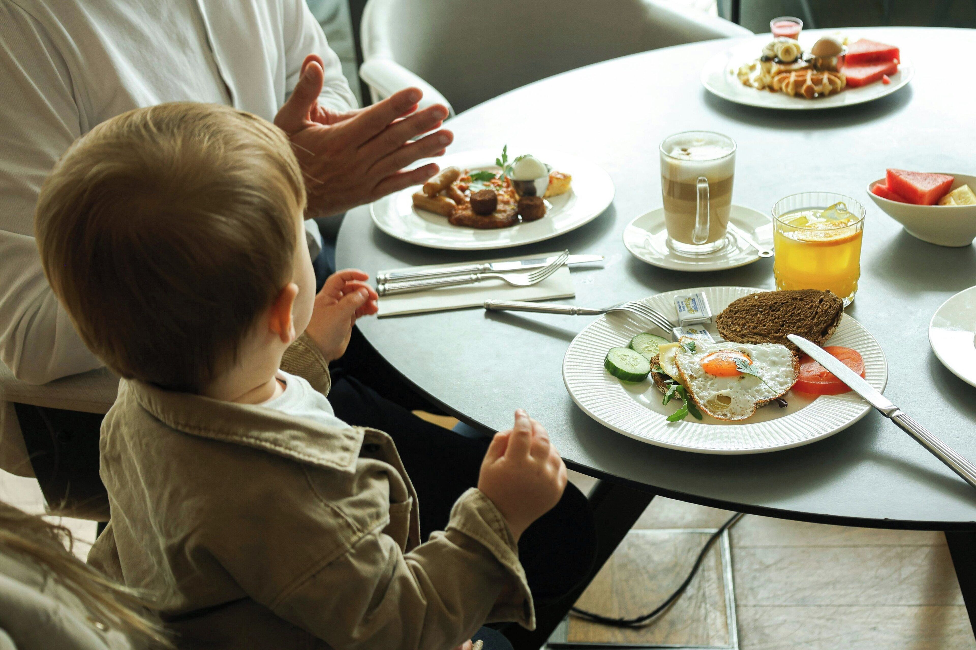 A dining table with plates of food, utensils, and a glass of juice.