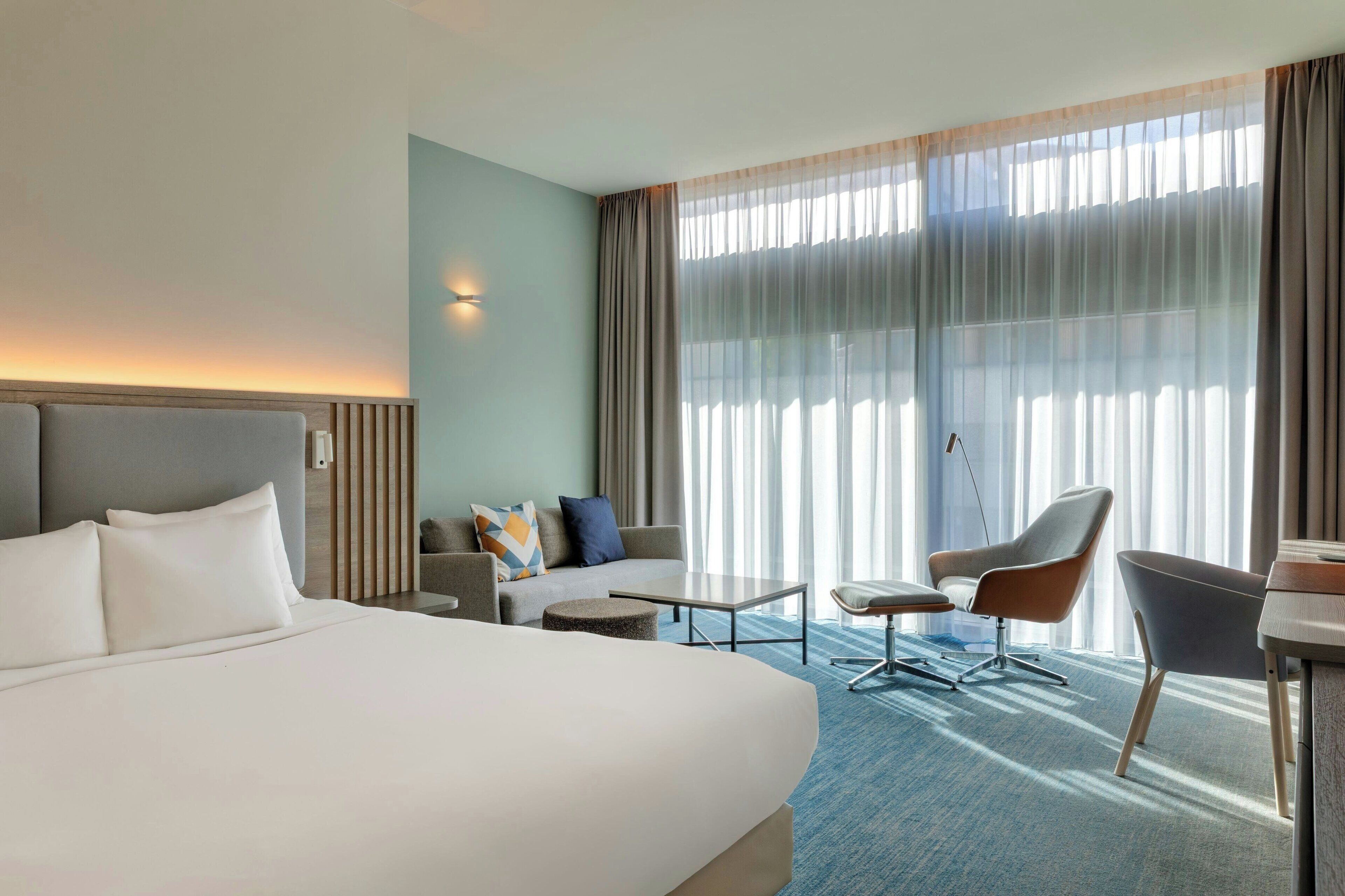 Een hotelkamer met een groot bed, een bank, een bureau en een stoel.