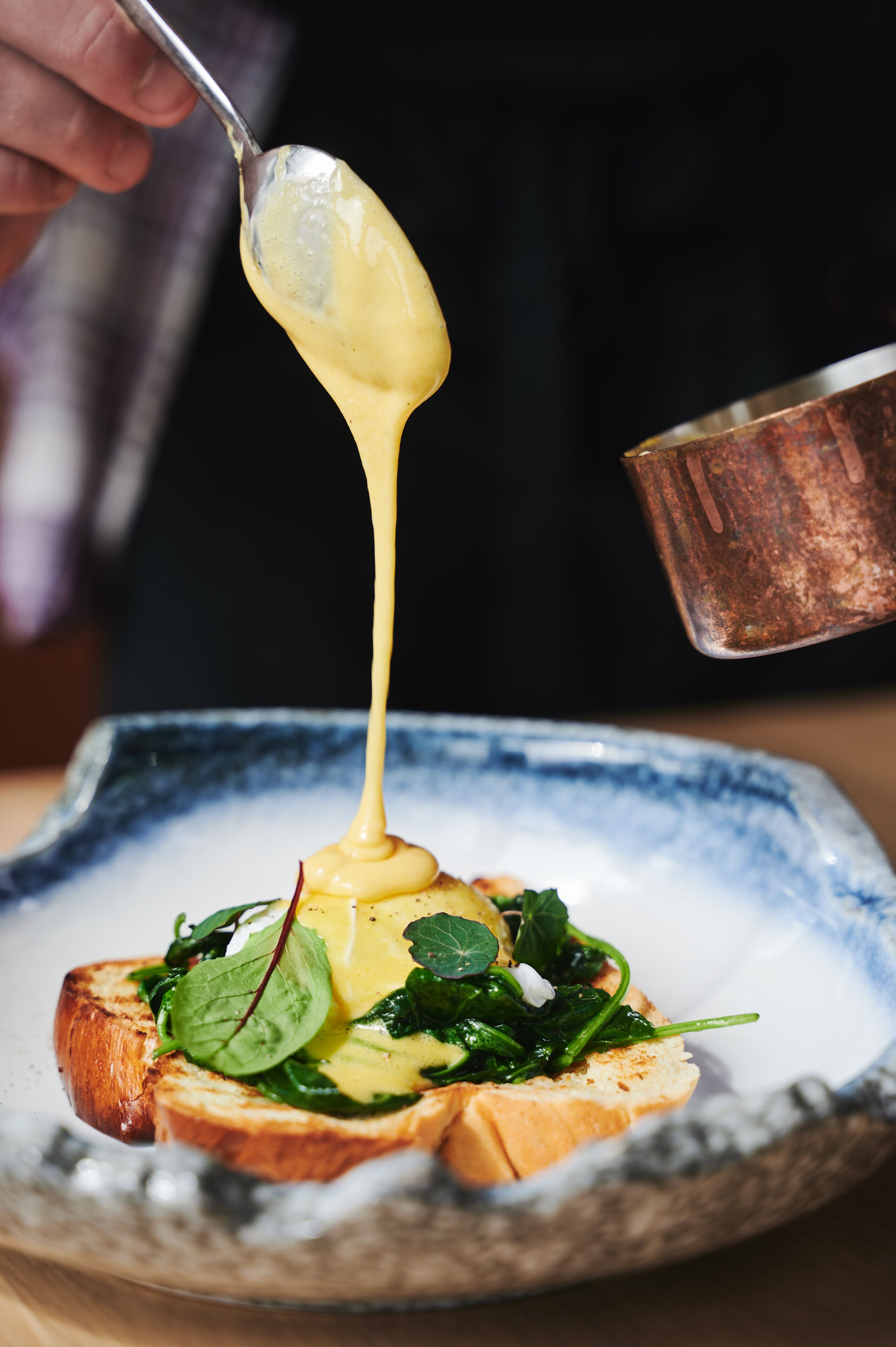 Soße wird über ein Gericht mit Toast und Grünzeug gegossen.