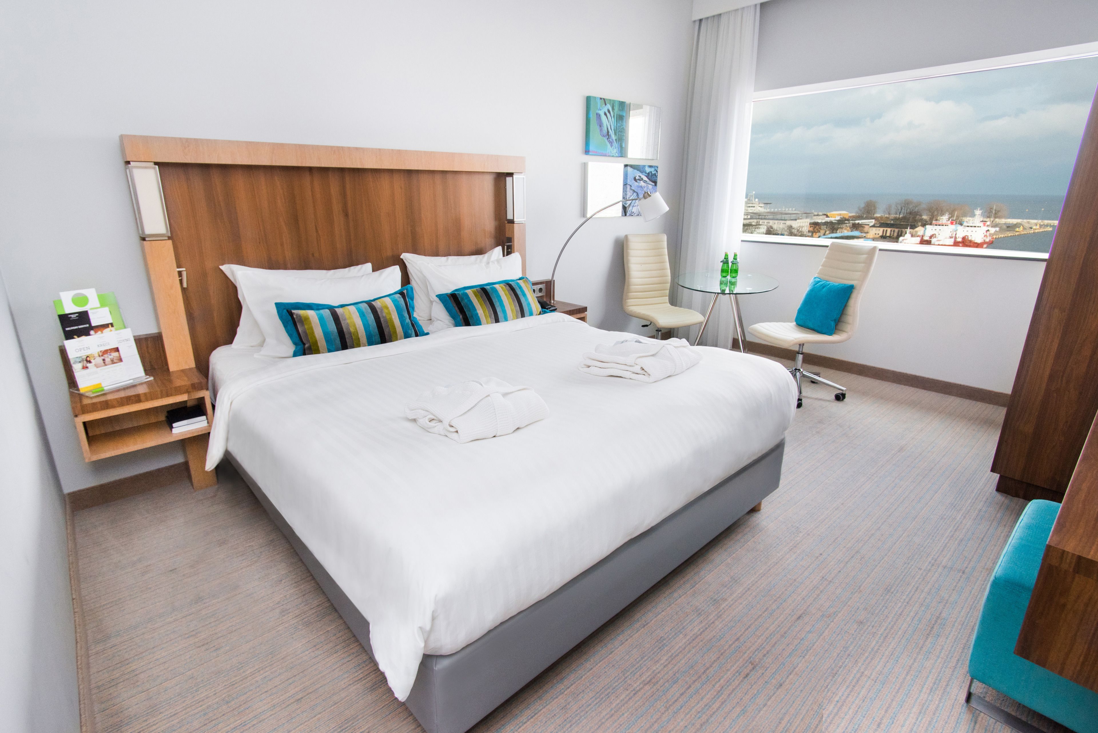Habitación de hotel con una cama grande, un escritorio, una silla y vista al mar.