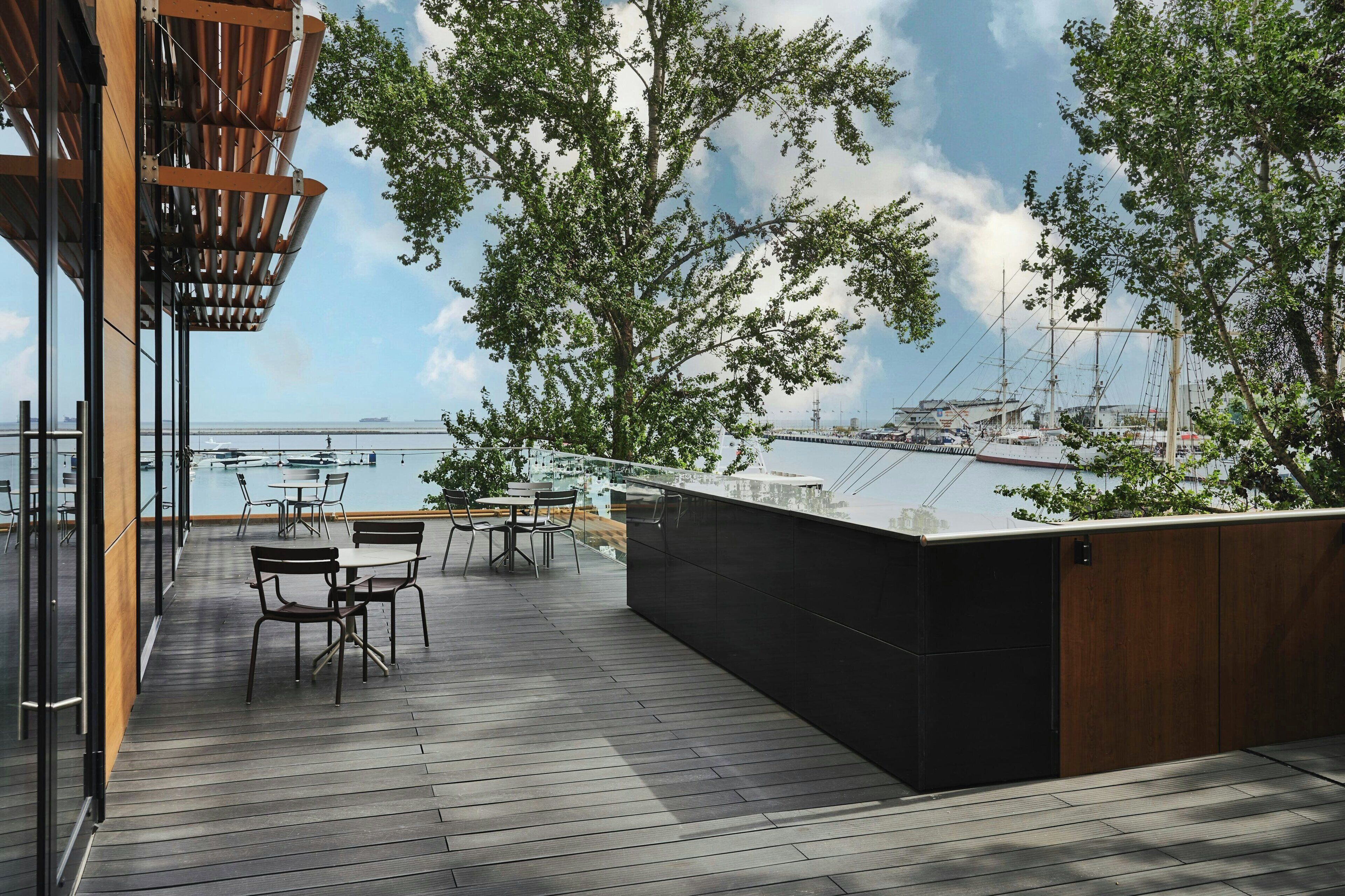 An outdoor deck with wooden flooring, metal railings, and a bar area.