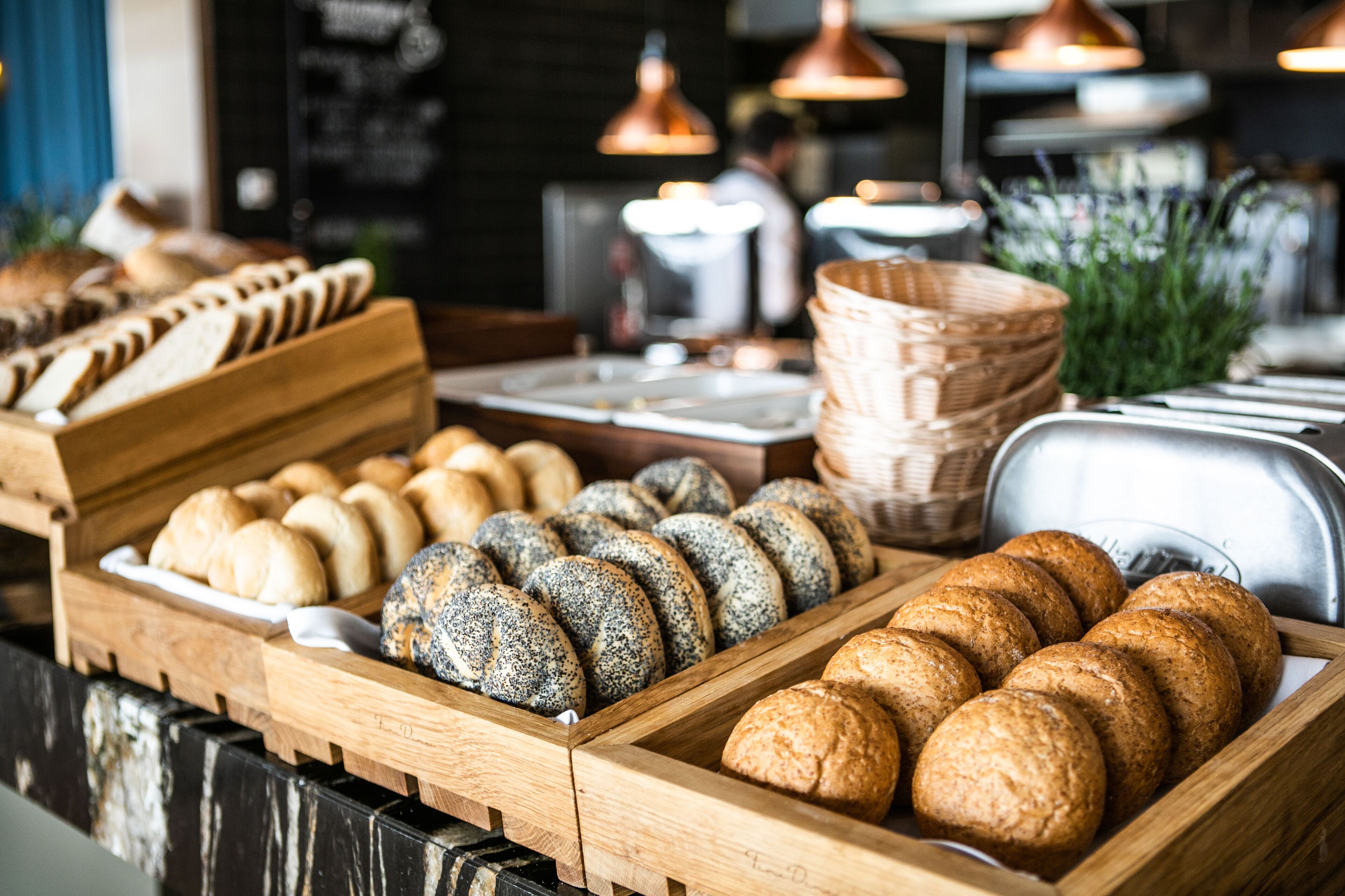 Una vitrina de panadería con distintos tipos de pan y pasteles en bandejas de madera.