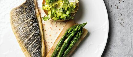 A plate with grilled fish, asparagus, and a salad.