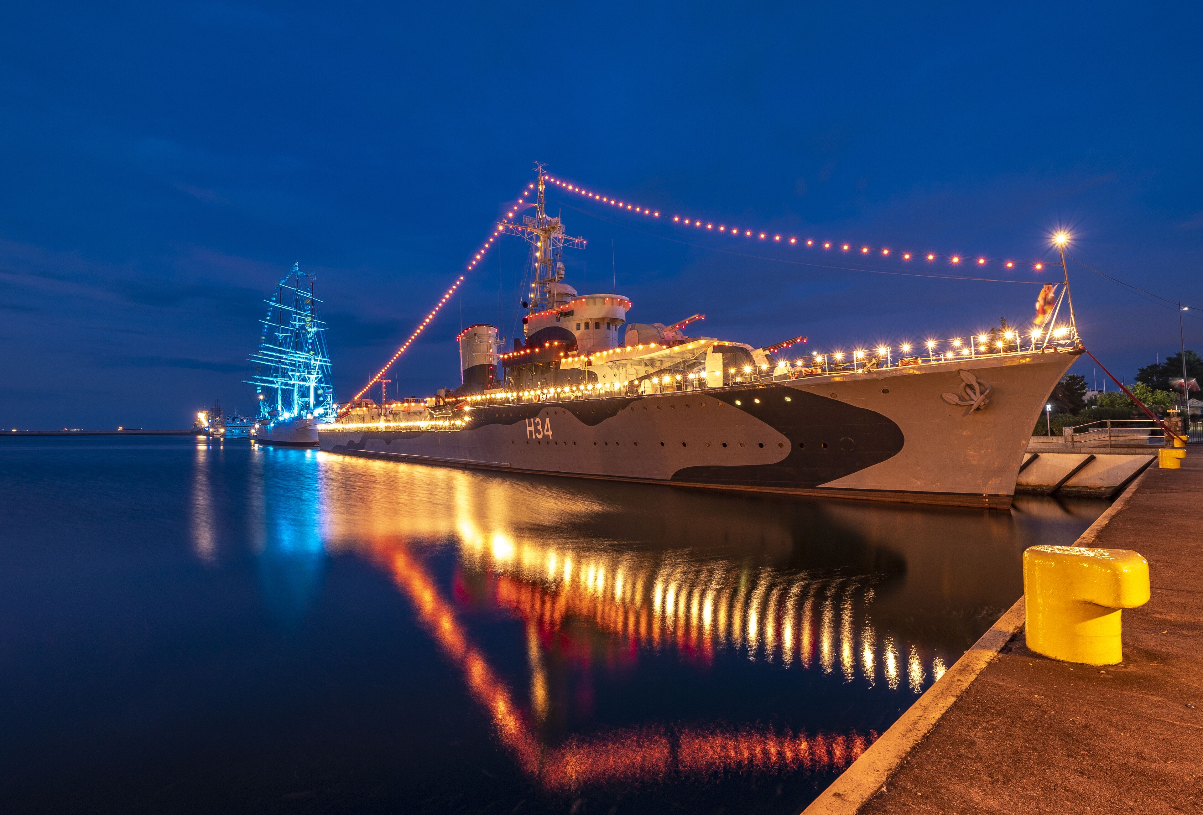 Un barco grande amarrado en un muelle, con luces reflejándose en el agua.