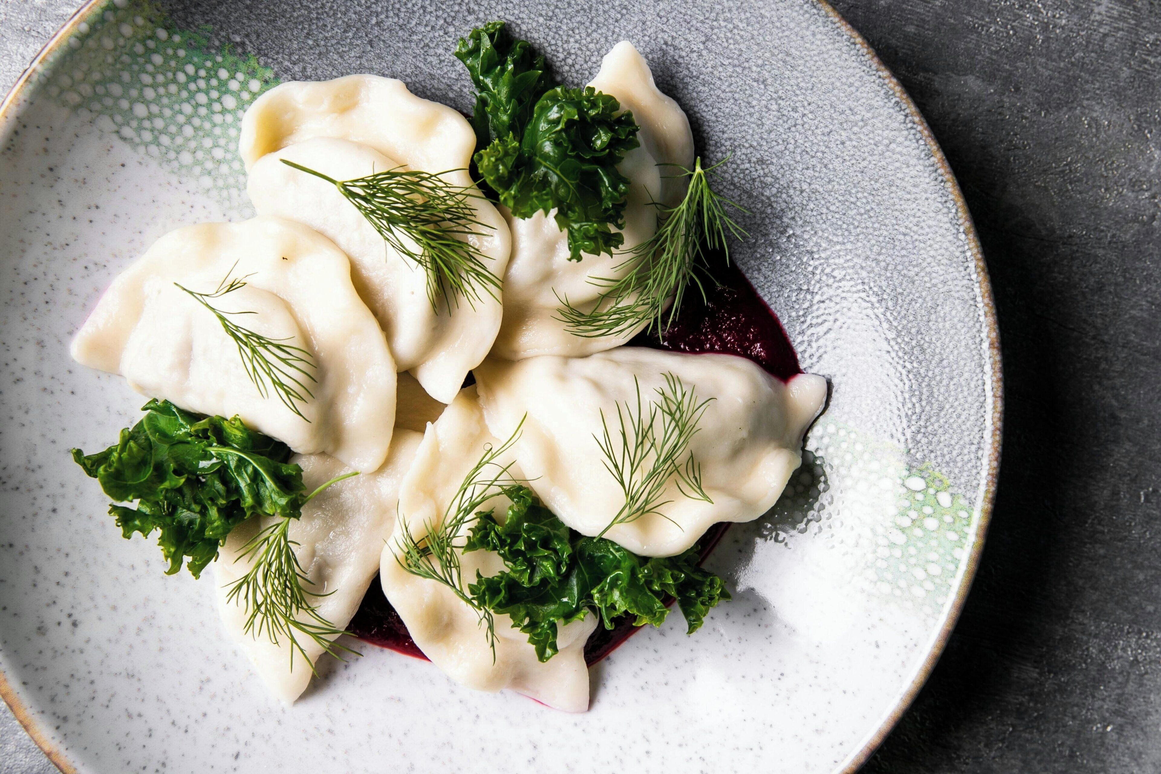 A plate of dumplings with greens and dill.
