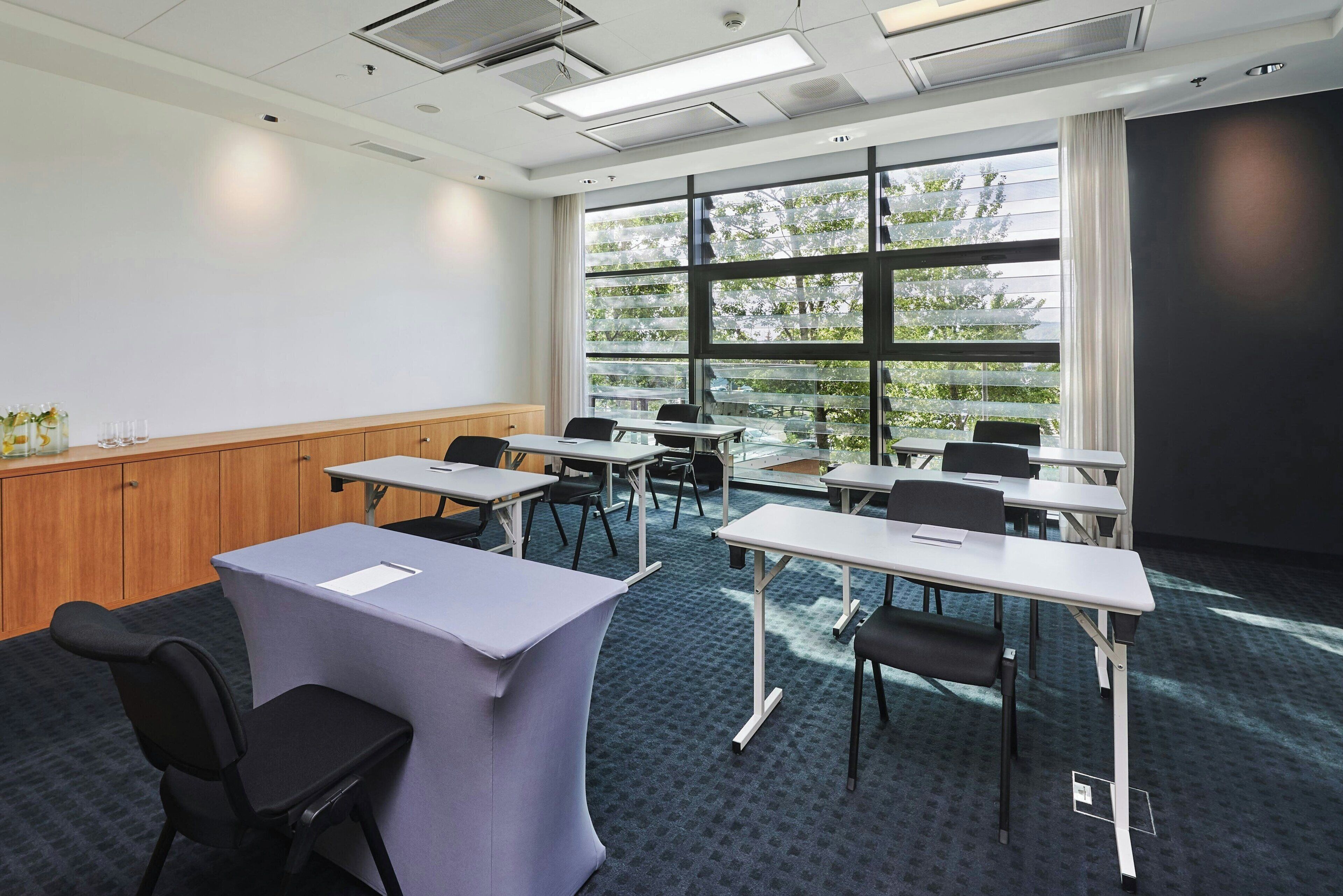 A conference room with a large window, multiple tables, and chairs.