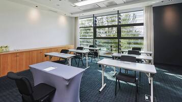 Un salón de conferencias con un amplio ventanal, varias mesas y sillas.
