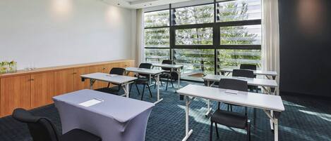 A conference room with a large window, multiple tables, and chairs.