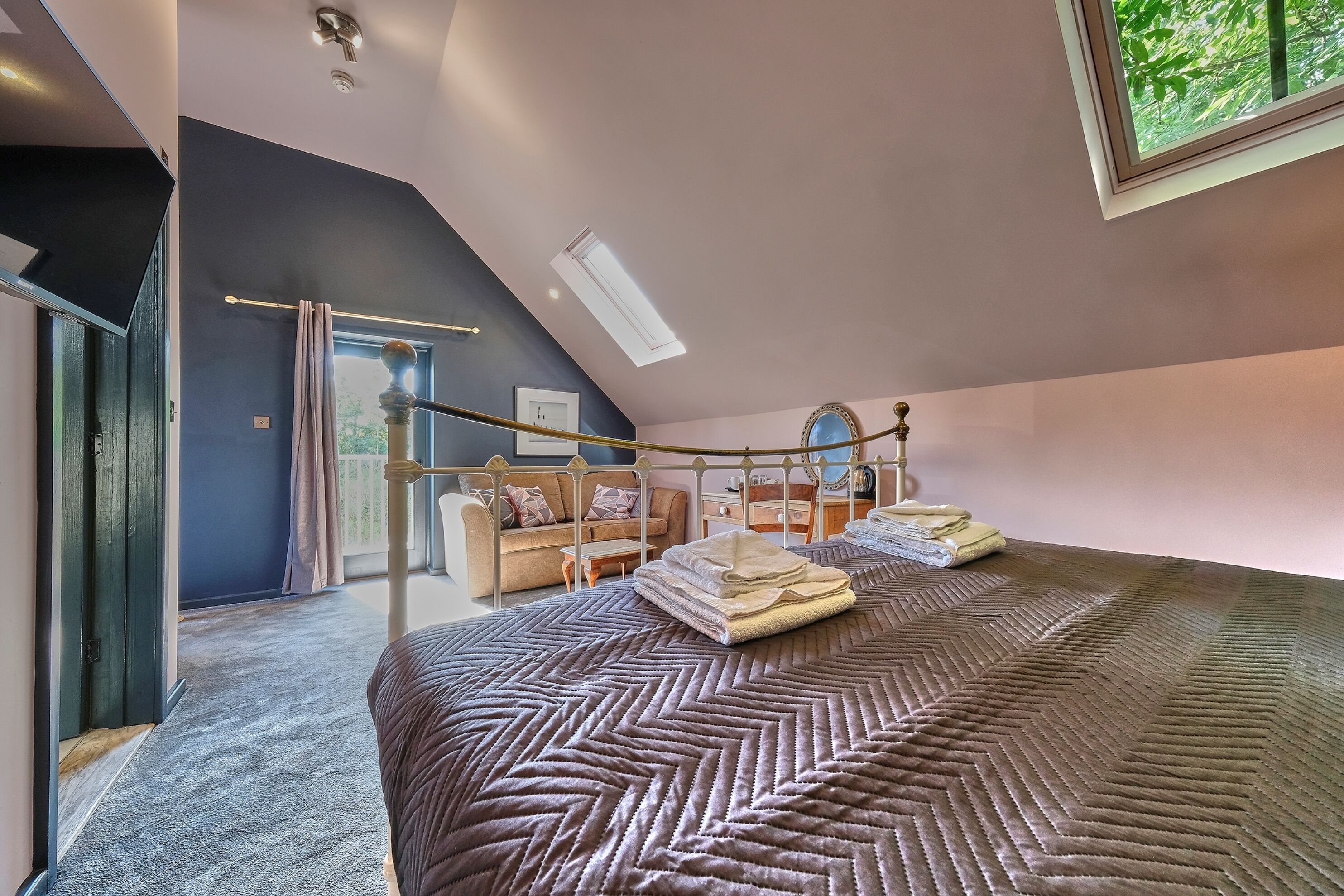 A bedroom with a large bed, a window, a ceiling fan, and a view of the outdoors.