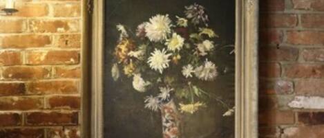 A rustic brick wall with a framed painting of flowers.