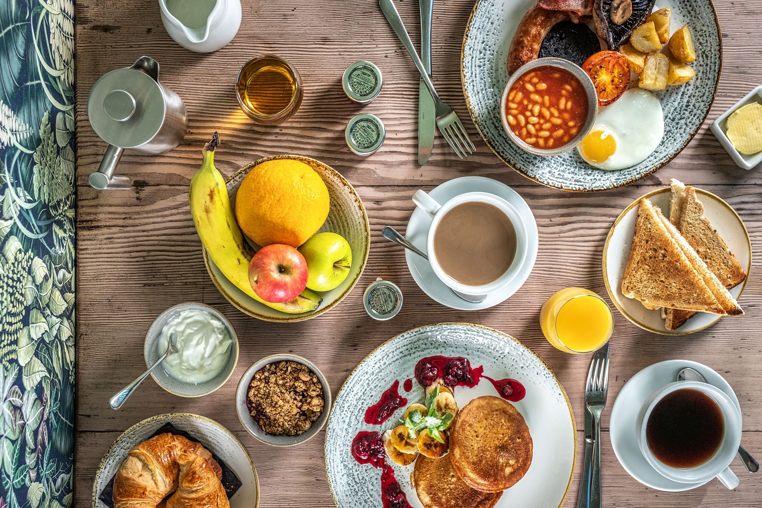 Uma mesa de madeira com uma variedade de pratos e bebidas para o café da manhã.
