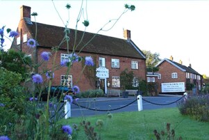 A traditional brick building with a sign for 'The Crown Inn' and 'The Crown Inn Accommodation & Caravan Gardens'.