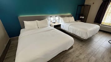 A hotel room with two beds, a nightstand with a lamp, a wardrobe, and a window with curtains.