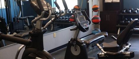 A gym with cardio machines, dumbbells, and a mirror.