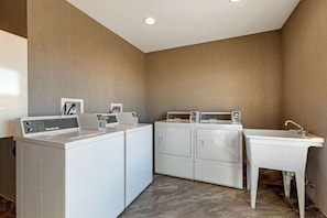 Convenient laundry facilities with washer and dryer, sink, and control panel.
