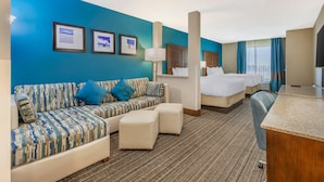 Een hotelkamer met een blauwe accentmuur, een bank, een bed, een bureau en een spiegel.