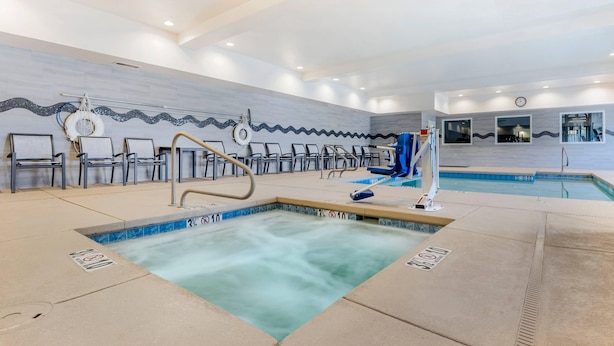 Een zwembadgedeelte met een jacuzzi, ligbedden en een badmeesterstand.