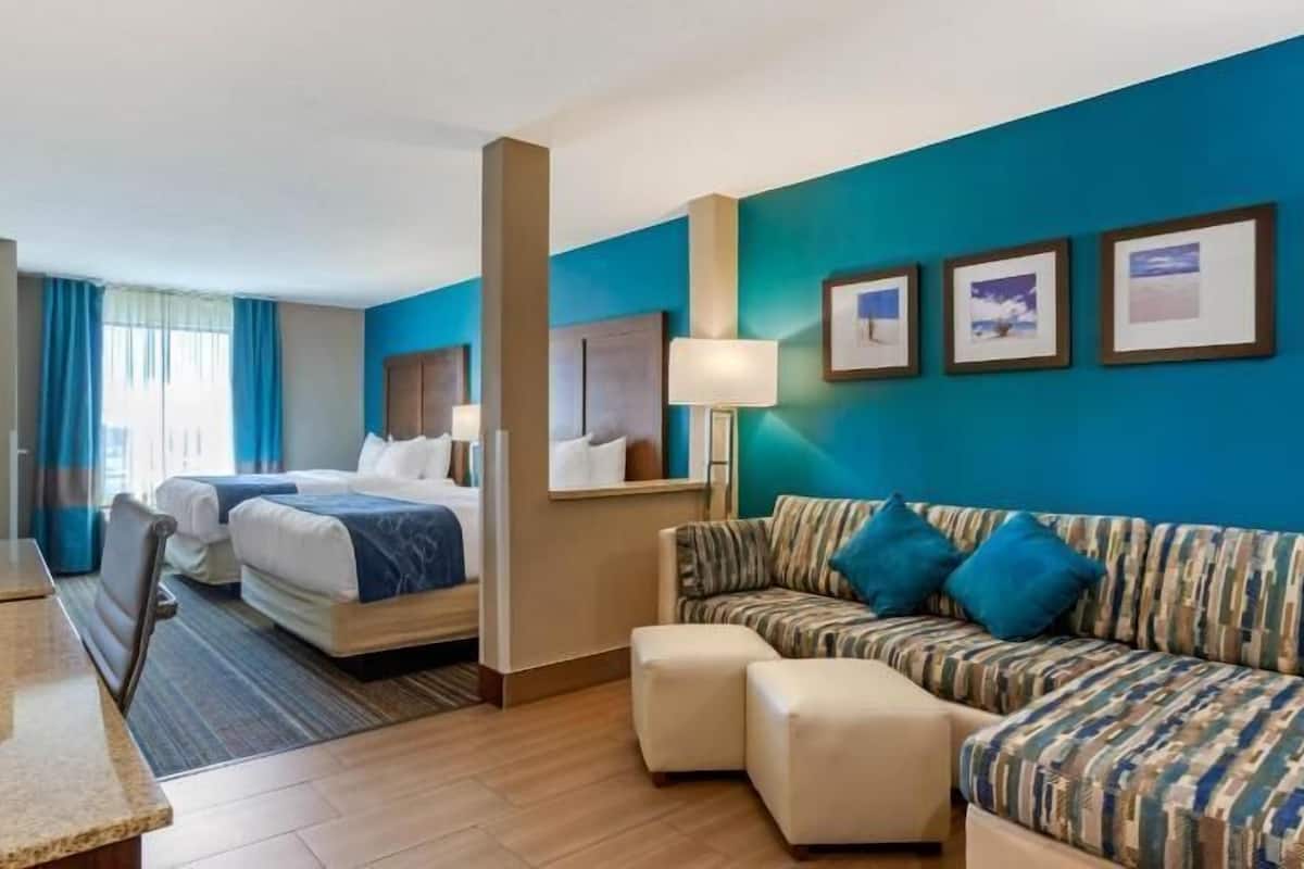 A hotel room with a bed, a sofa, a desk, and a mirror.