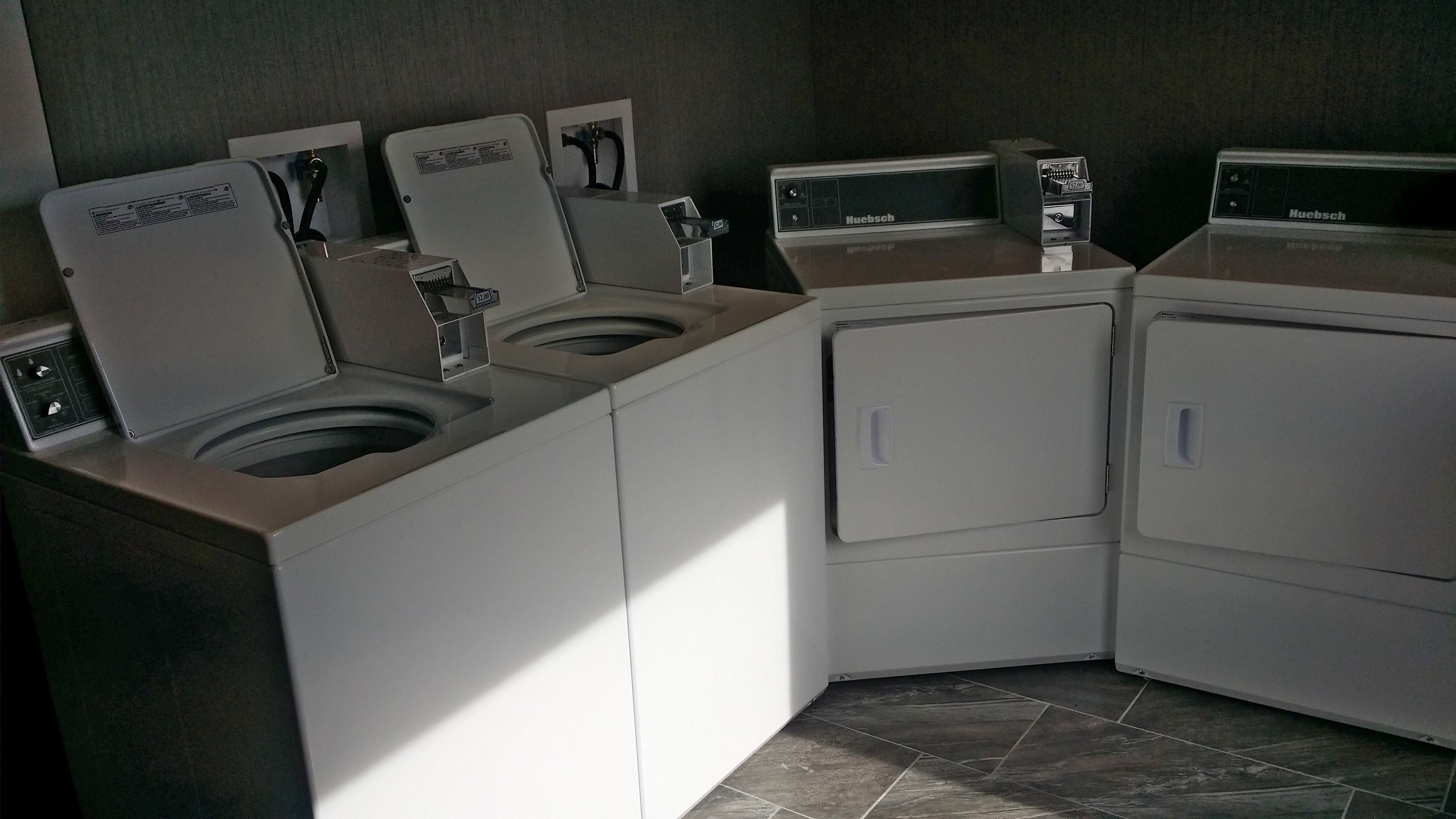 A laundry room with multiple washing machines and dryers, including a front-loading washer and a top-loading dryer.