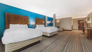 A hotel room with two beds, a desk, and a chair.