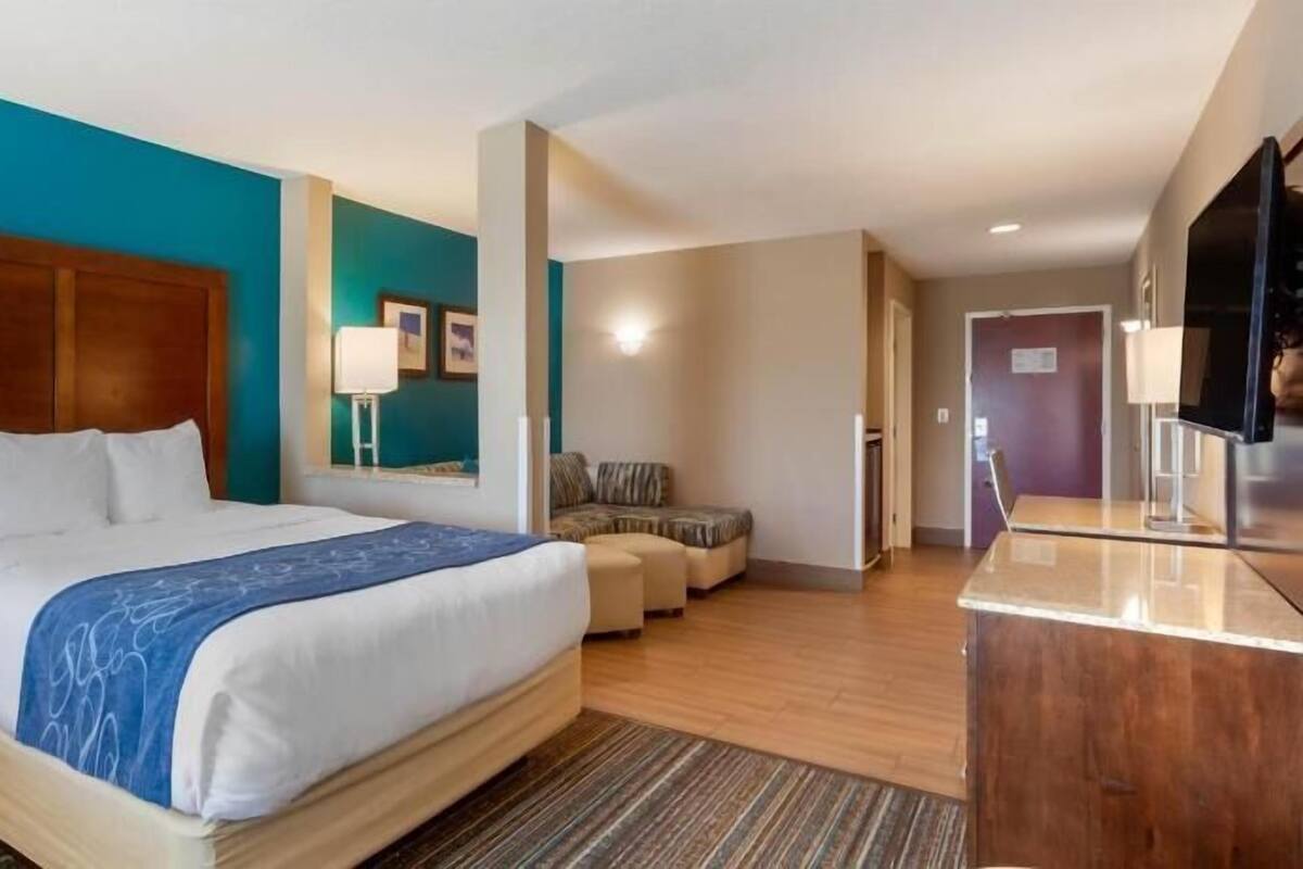A hotel room with a large bed, a desk, a chair, and a television.