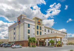 Un hôtel Comfort Suites avec un ciel dégagé et quelques nuages.