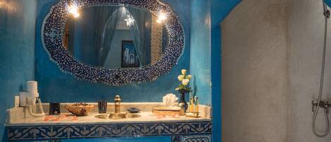 Un baño con una decoración azul y blanca, un espejo grande y una zona de ducha.