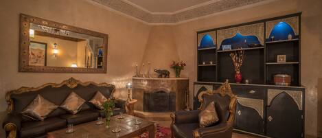 A traditional living room with a fireplace, ornate furniture, and a decorative mirror.