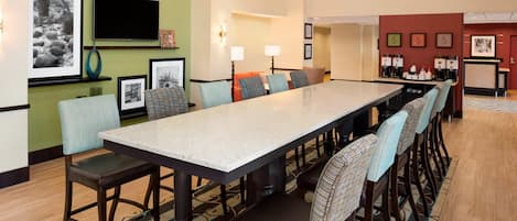 Un comedor de hotel con una mesa larga, sillas y una estación de café.