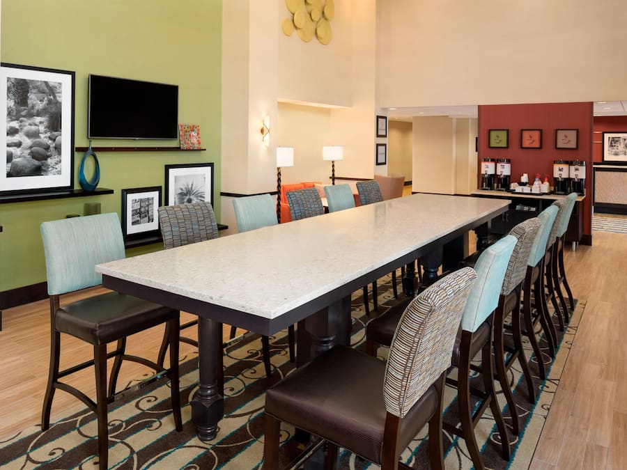 A hotel dining area with a long table, chairs, and a coffee station.