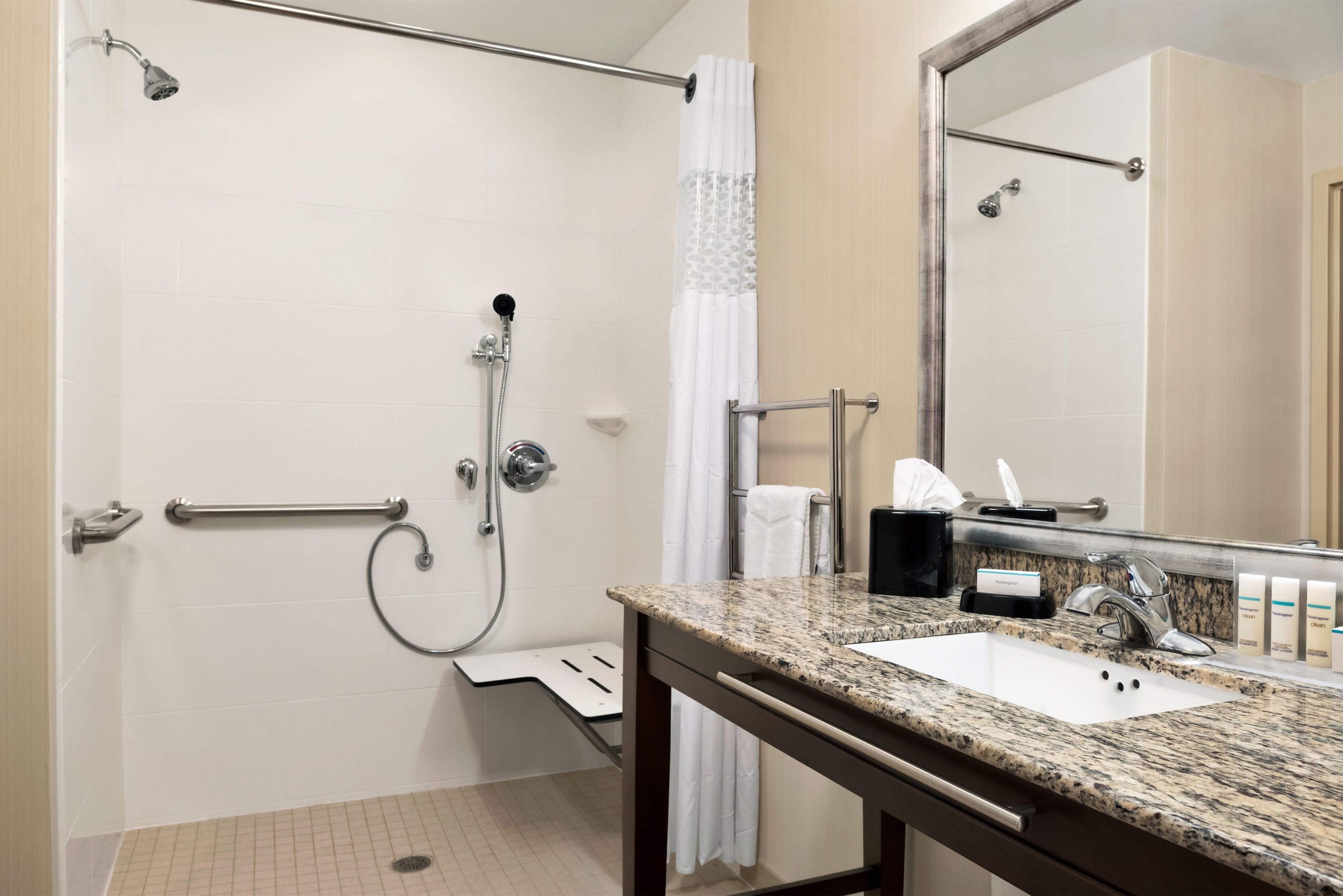 A bathroom with a shower, a sink, a mirror, and a towel rack.