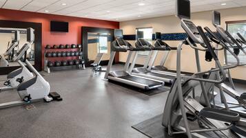 A gym with treadmills, elliptical machines, and dumbbells.