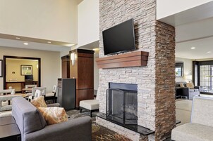 Una sala de estar moderna con chimenea de piedra, asientos cómodos y un televisor de pantalla plana sobre la chimenea.