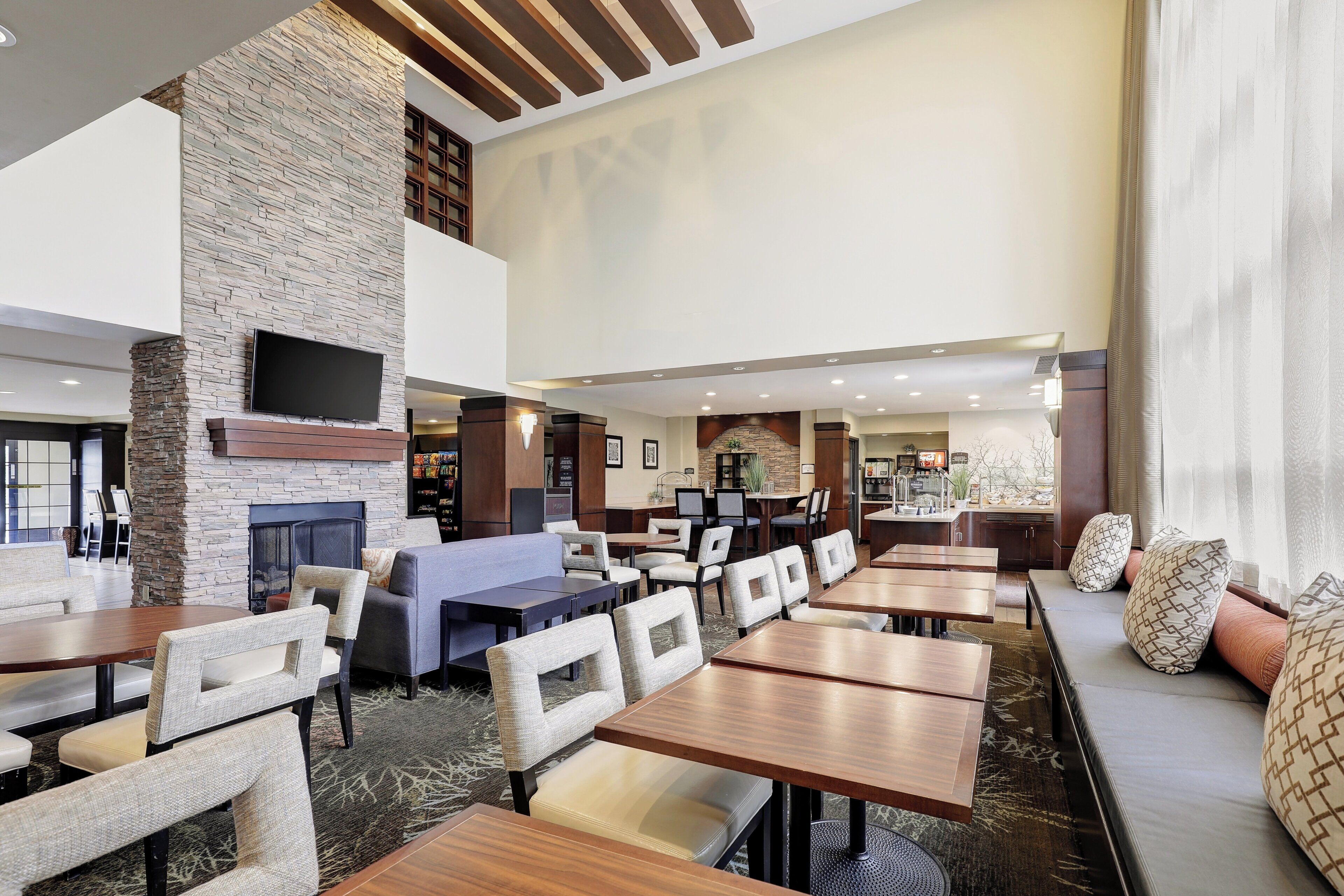 A spacious indoor area with multiple seating arrangements, including tables and chairs, and a fireplace.