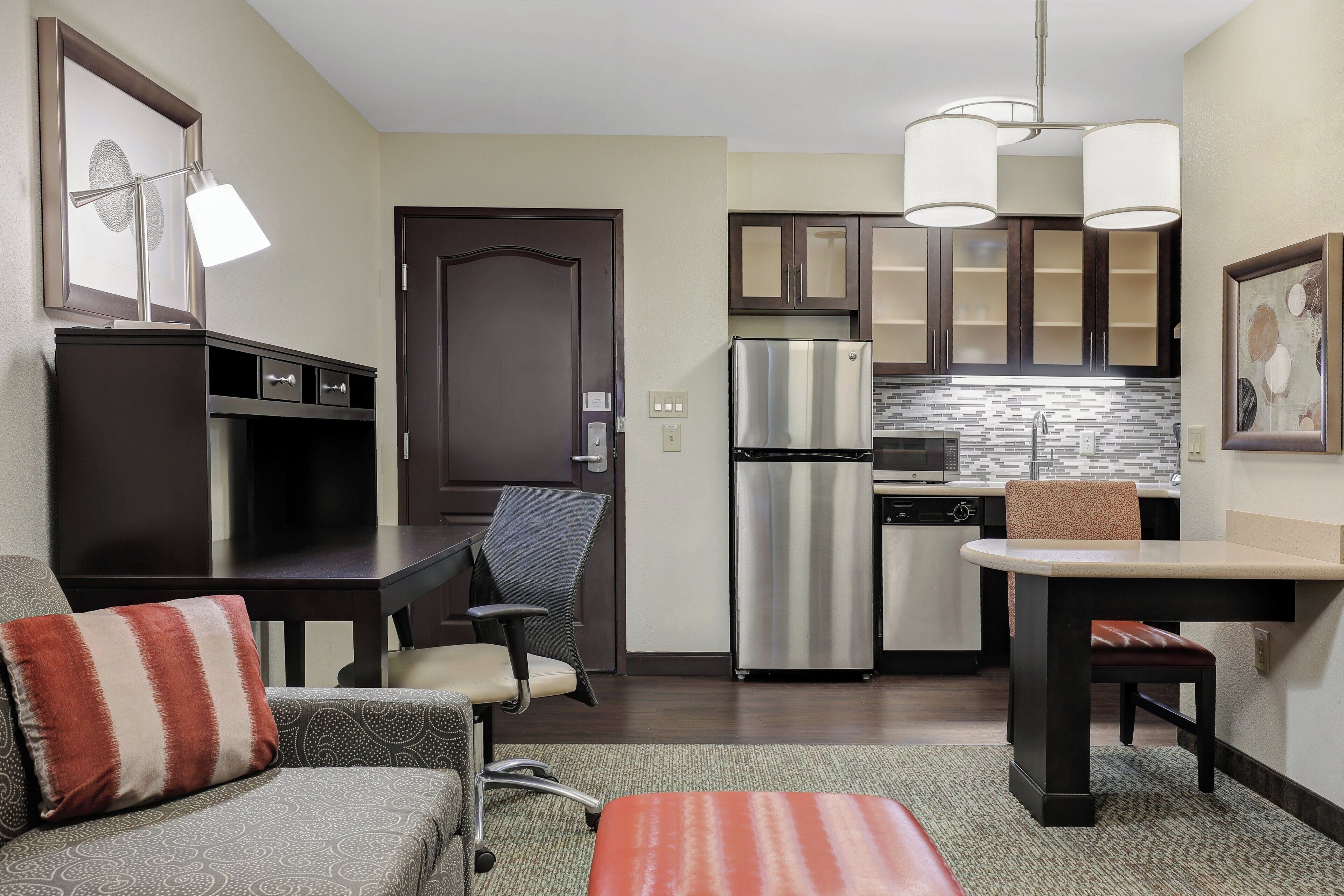 A compact kitchen with a refrigerator, microwave, and a dining area with a chair and table.
