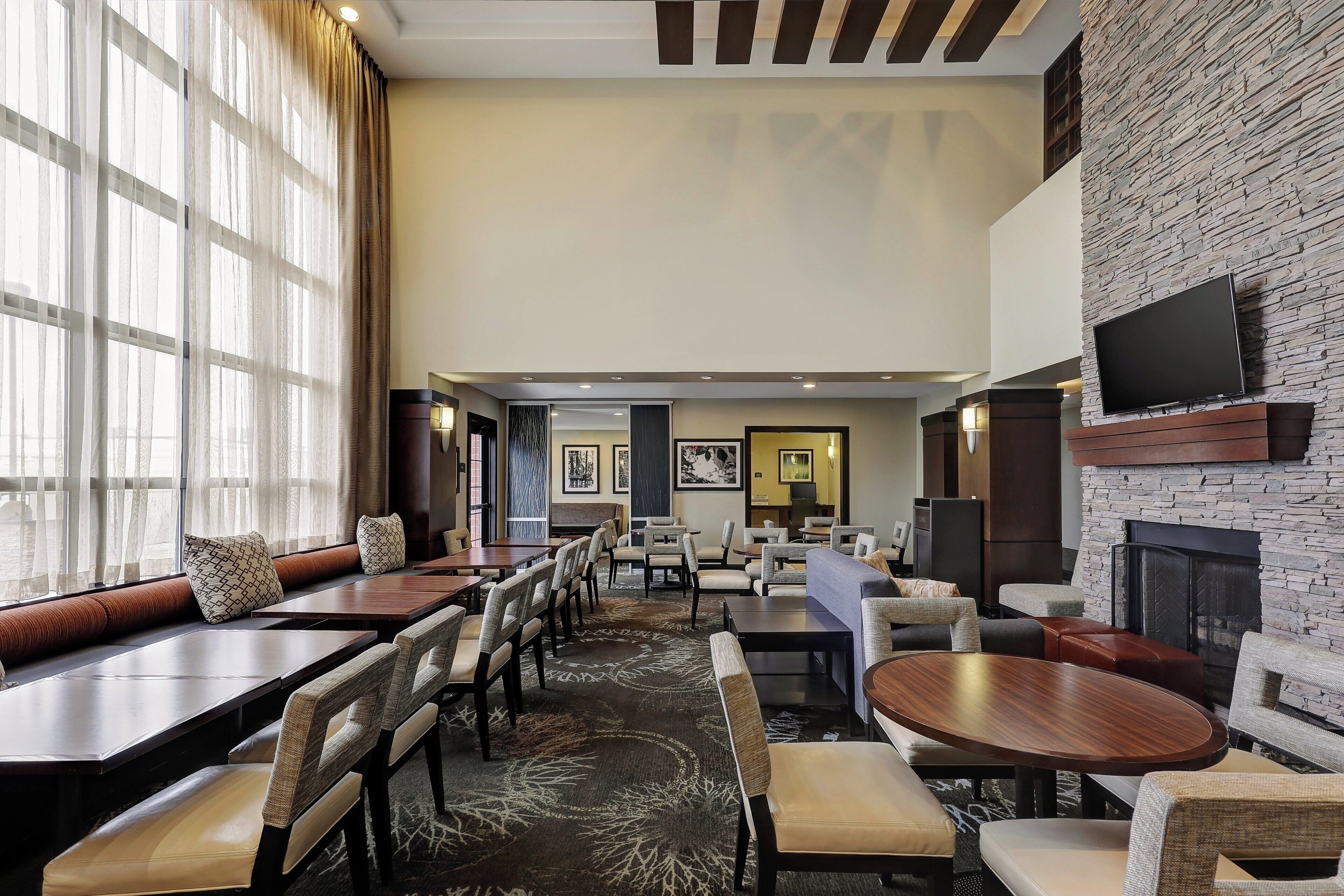 A hotel lobby with multiple seating areas, including sofas and tables, a fireplace, and artwork on the walls.