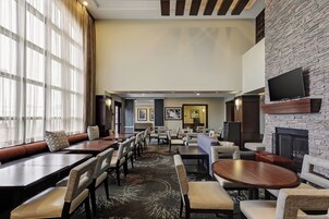 Un hall de hotel con varias zonas de estar, que incluyen sofás y mesas, una chimenea y obras de arte en las paredes.